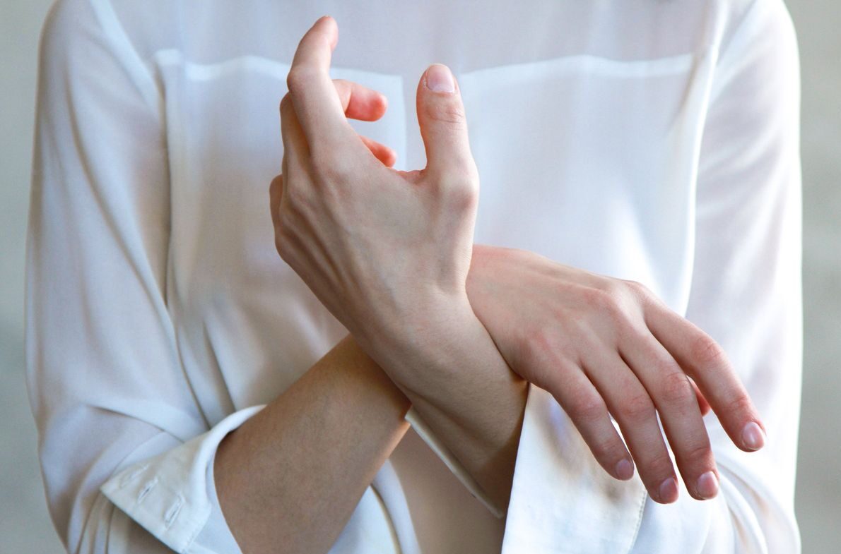 Elegant hands in a white shirt gently touching each other, symbolizing calm and tenderness.